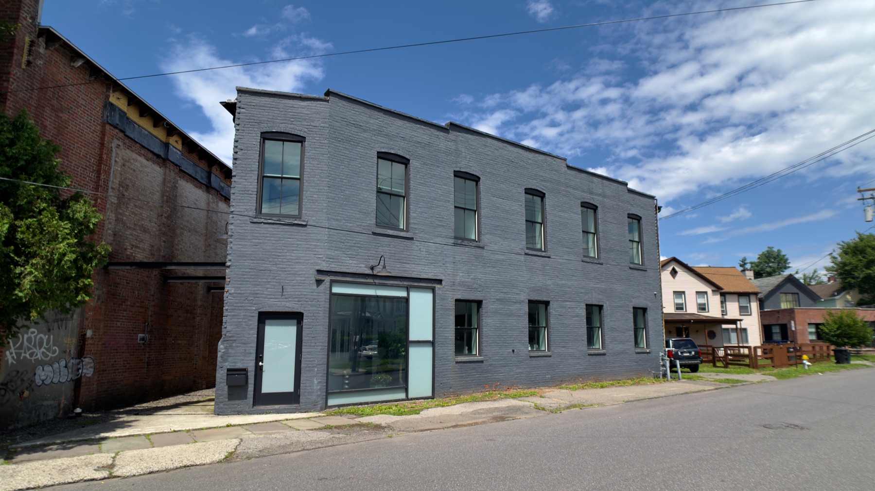 Gray-brick factory facade on Prince Street under a blue sky